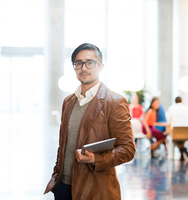 Stylish model wearing a cognac leather blazer in fall foliage, showcasing transitional fashion trends.