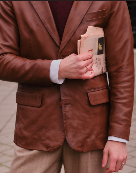 Model holding newspaper and wearing a brown mens leather blazer from Cycas d'Or